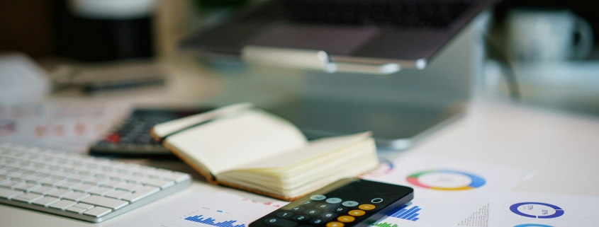 Calculatrice et graphiques financiers sur un bureau — comparatif coût secrétaire salariée vs externalisée