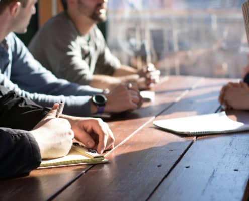 Personnes en réunion professionnelle prenant des notes pour retranscription