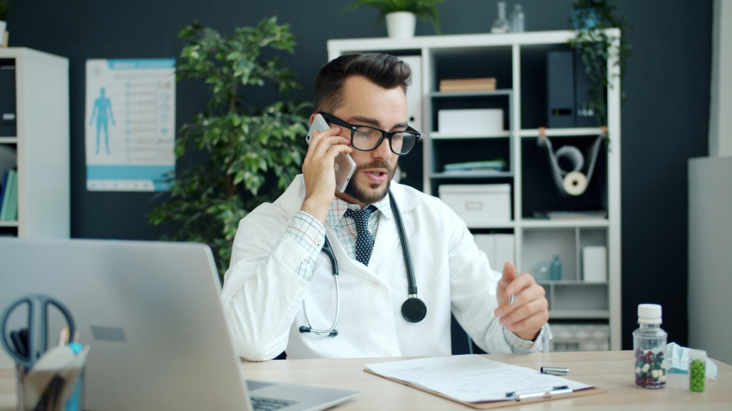 Médecin généraliste en cabinet dictant à distance pour son secrétariat médical externalisé