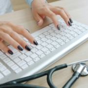 doctor typing medical report computer Professionnel de santé rédigeant un compte-rendu médical, illustrant les limites de la transcription par IA