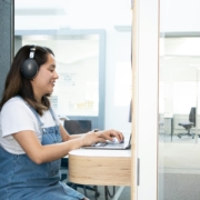 woman typing headset transcription office focused Secrétaire virtuelle concentrée, casque audio, relisant un document de transcription sur son écran d'ordinateur