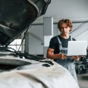 Expert automobile : rapports et échanges réparateurs Expert automobile inspectant un véhicule endommagé chez un réparateur